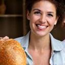 Marie Dupont souriante brandissant un pain rustique qu'elle a confectionné.