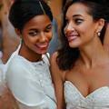 Photo d'un couple souriant posant devant leur gâteau de mariage, l'air très heureux, lors de leur réception.
